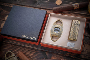 Antique bronze cutter and lighter in an open gift box, the black lid engraved with a name