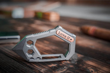 Titanium carabiner tool on its side, the copper plate engraved with a short phrase